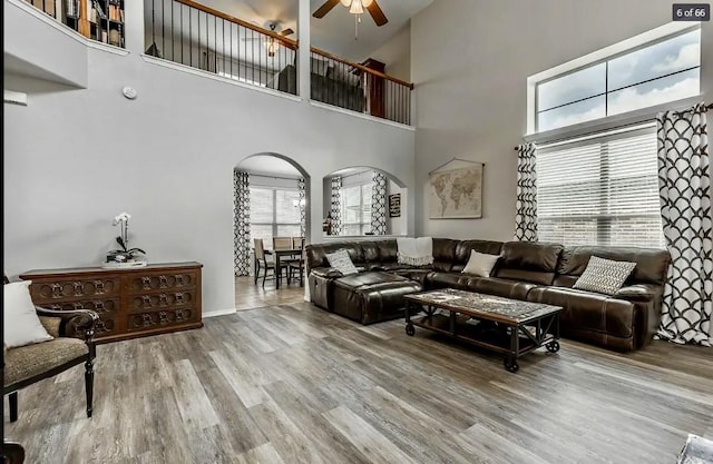 living room featuring hardwood / wood-style flooring, a high ceiling, and ceiling fan