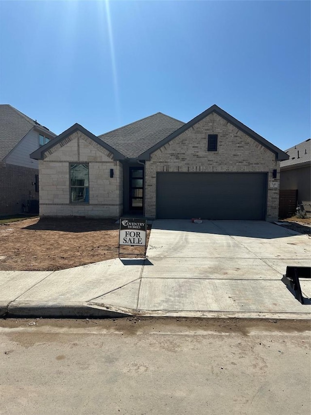 view of front of home featuring a garage, concrete driveway, and brick siding