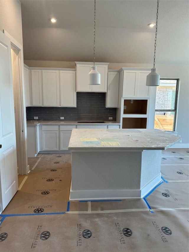 kitchen featuring decorative light fixtures, cooktop, white cabinetry, and decorative backsplash