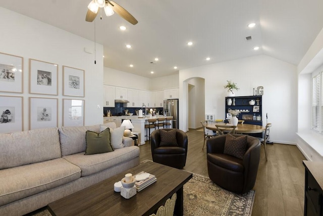 living room featuring high vaulted ceiling, ceiling fan, and light wood-type flooring