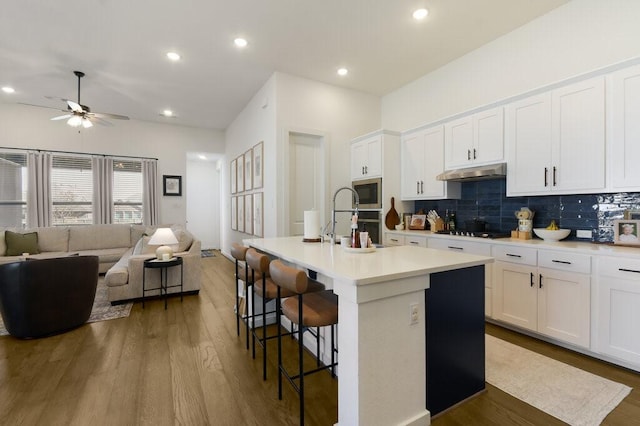 524 Calmo Ct, Liberty Hill, TX 78642 - kitchen featuring open floor plan, a ceiling fan, backsplash, a breakfast bar area, and wood finished floors
