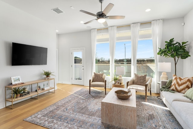 living room with hardwood / wood-style floors, a water view, and ceiling fan