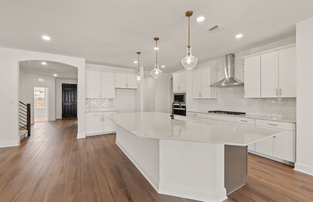 3813 Gabriels Horn Rd, Leander, TX 78641 - kitchen with wall chimney exhaust hood, tasteful backsplash, a large island, arched walkways, and recessed lighting