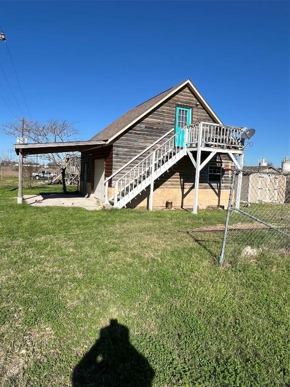 rear view of house with a deck, a patio area, and a lawn