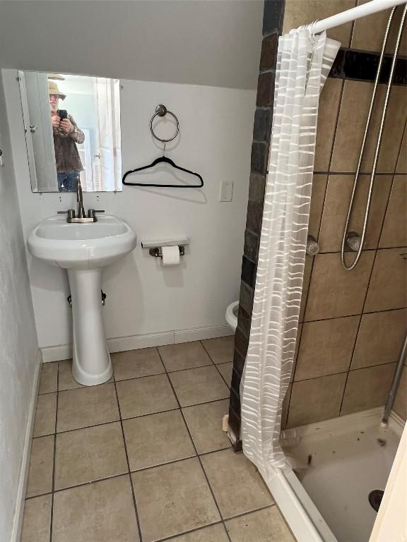 bathroom featuring tile patterned floors, toilet, curtained shower, and sink