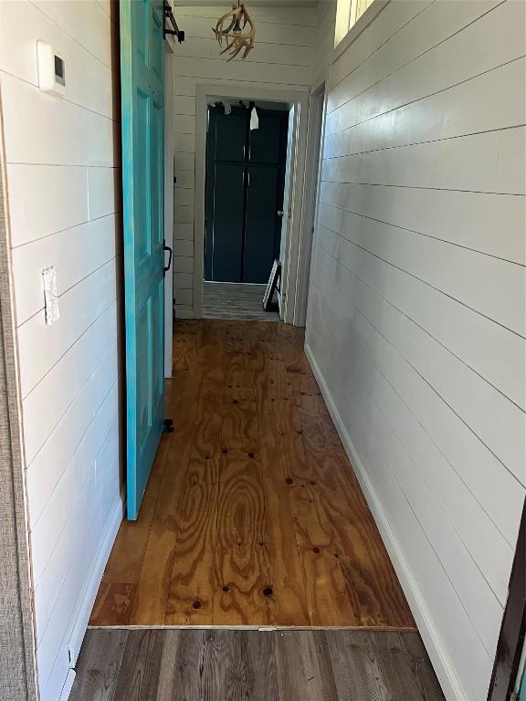 hall with dark hardwood / wood-style flooring and wood walls