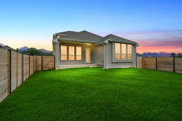 409 Raleigh Dr, Georgetown, TX 78633 - back of house at dusk featuring brick siding, a fenced backyard, and roof with shingles