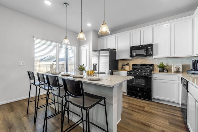 kitchen with pendant lighting, a center island, white cabinets, and black appliances