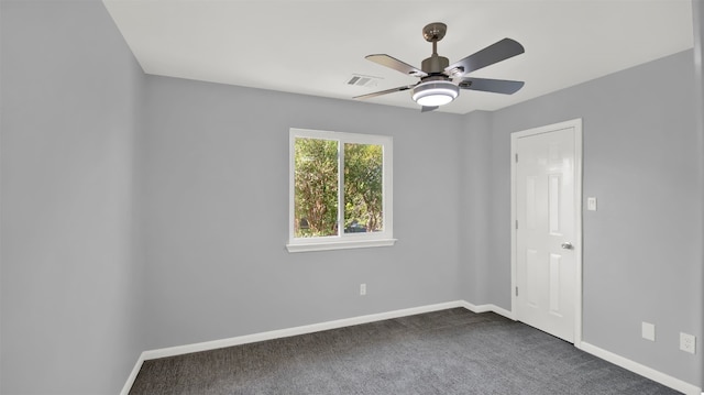 empty room with ceiling fan and dark colored carpet