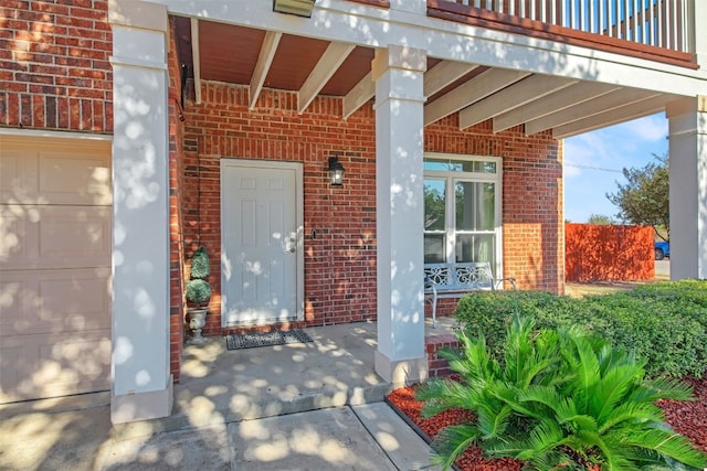 entrance to property featuring covered porch, a balcony, and a garage