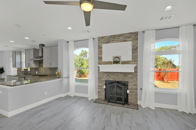 unfurnished living room with ceiling fan, a fireplace, and sink