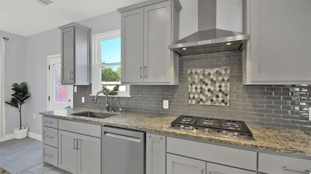 kitchen featuring light stone countertops, sink, wall chimney exhaust hood, decorative backsplash, and appliances with stainless steel finishes