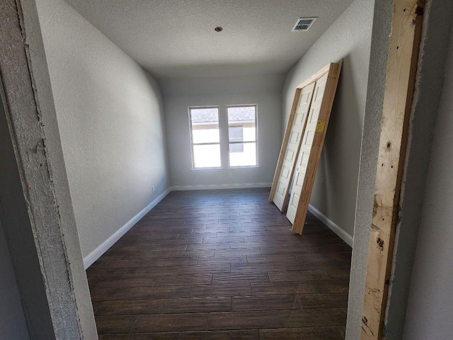 hall featuring dark wood finished floors, visible vents, and baseboards