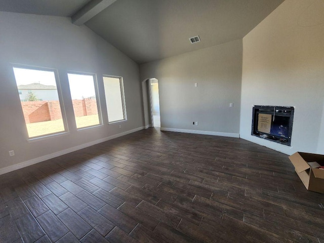 unfurnished living room with arched walkways, dark wood-type flooring, visible vents, baseboards, and beamed ceiling