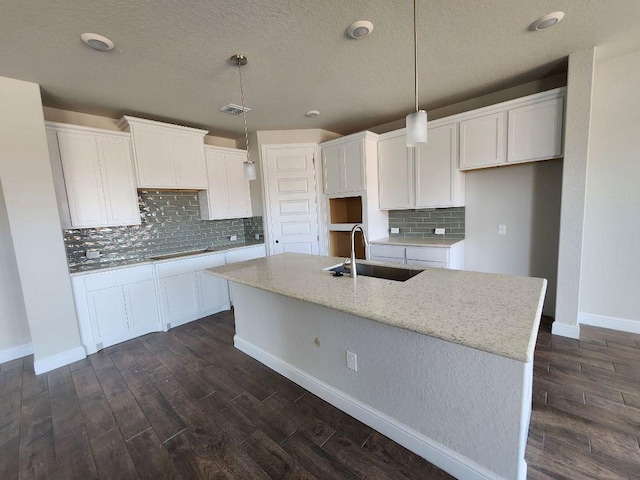 kitchen with an island with sink, a sink, and white cabinetry