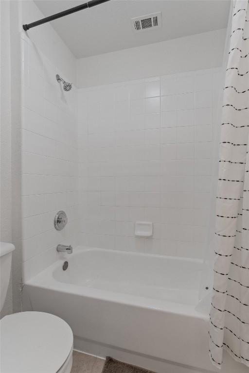 bathroom featuring tile patterned flooring, shower / bath combo, and toilet