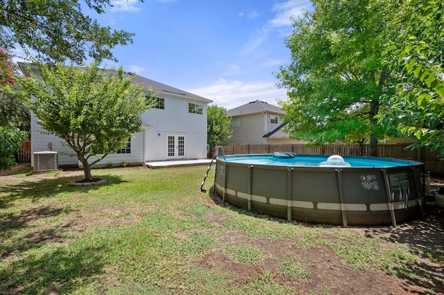 view of yard featuring cooling unit, a fenced in pool, and french doors