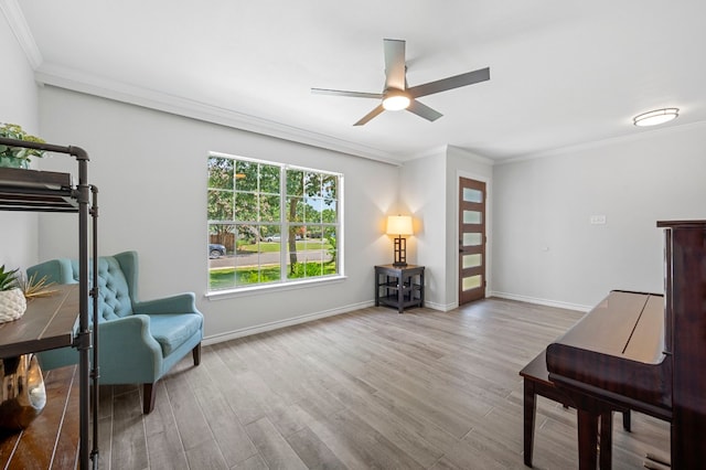 sitting room featuring wood-type flooring, ornamental molding, and ceiling fan