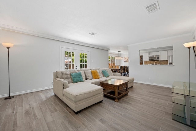 living room with crown molding, light wood-type flooring, and french doors