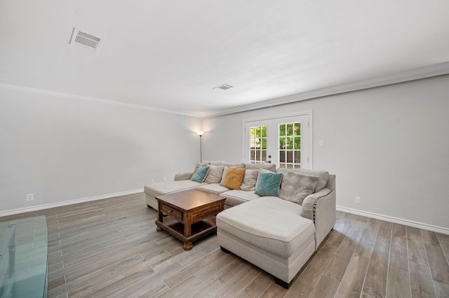 living room with french doors, crown molding, and light wood-type flooring