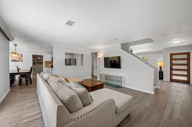 living room featuring ornamental molding and light hardwood / wood-style flooring