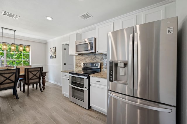 kitchen featuring appliances with stainless steel finishes, decorative light fixtures, white cabinetry, backsplash, and light stone counters