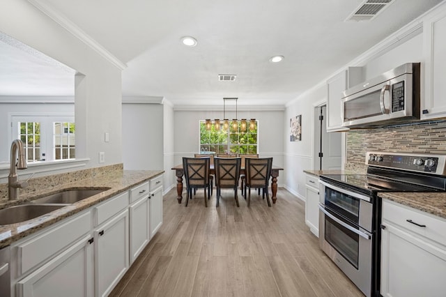 kitchen with white cabinetry, stainless steel appliances, light stone countertops, and sink