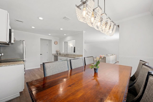 dining space with hardwood / wood-style flooring, crown molding, and sink