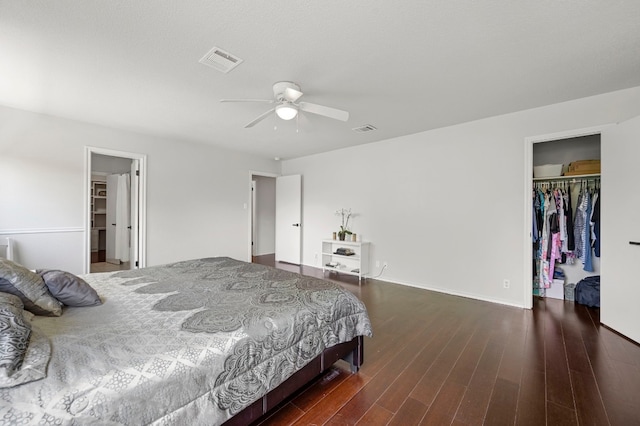 bedroom featuring a closet, a walk in closet, dark hardwood / wood-style floors, and ceiling fan