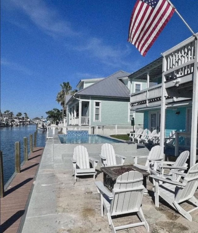 view of patio / terrace with a fire pit, a water view, and a balcony