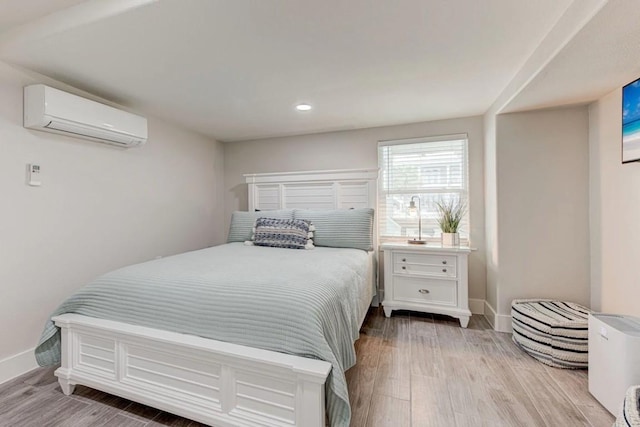 bedroom with an AC wall unit and light hardwood / wood-style flooring