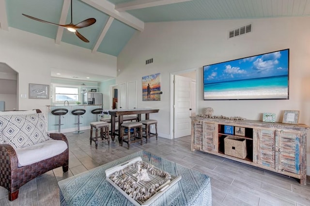 living room featuring beam ceiling, high vaulted ceiling, and ceiling fan