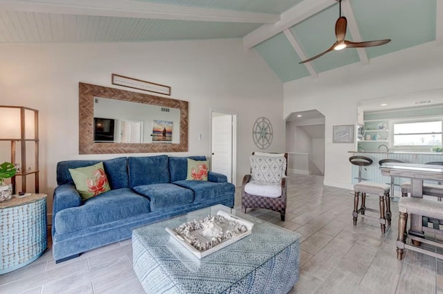 living room featuring beamed ceiling, ceiling fan, and high vaulted ceiling