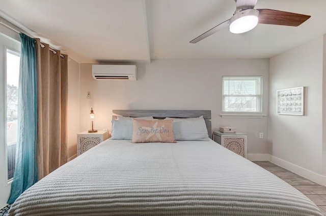 bedroom with multiple windows, ceiling fan, a wall mounted air conditioner, and light wood-type flooring