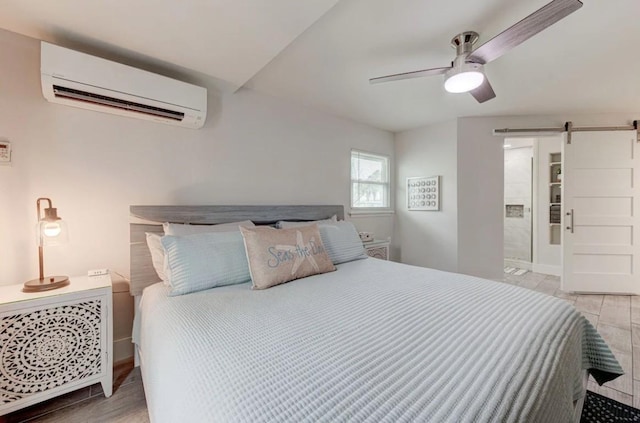 bedroom with ceiling fan, a barn door, and a wall unit AC