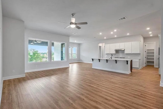 unfurnished living room featuring sink and light hardwood / wood-style floors