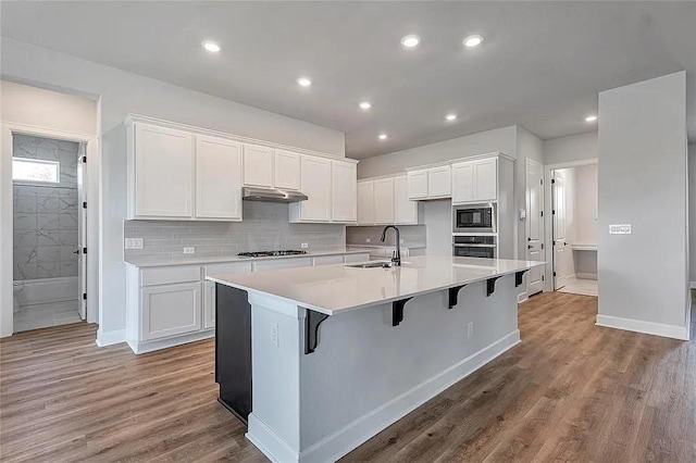 kitchen featuring white cabinets, appliances with stainless steel finishes, an island with sink, and sink