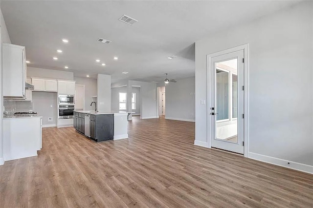 kitchen with a kitchen island with sink, white cabinets, sink, ceiling fan, and appliances with stainless steel finishes