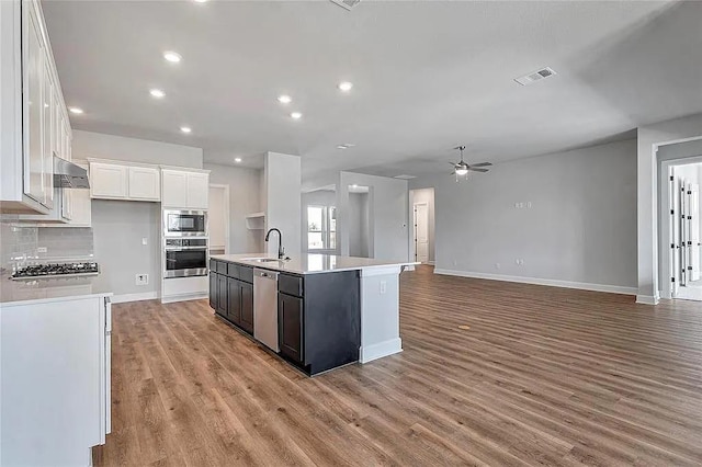 kitchen featuring white cabinets, sink, an island with sink, tasteful backsplash, and stainless steel appliances