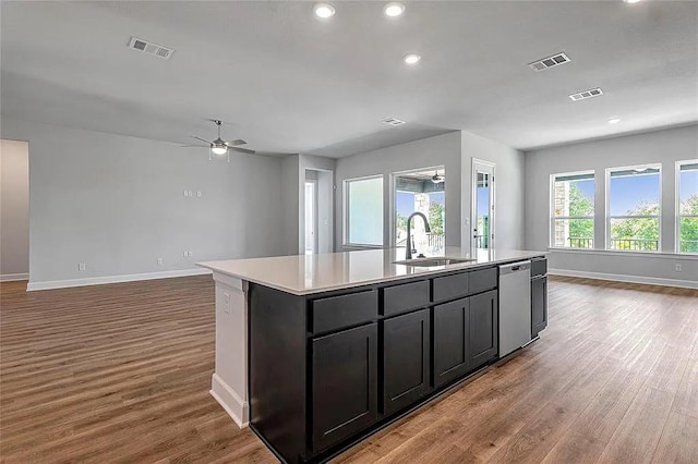 kitchen featuring ceiling fan, sink, stainless steel dishwasher, a center island with sink, and hardwood / wood-style flooring