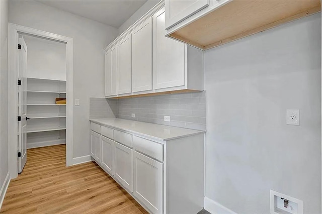 laundry room with cabinets, hookup for a washing machine, and light hardwood / wood-style flooring