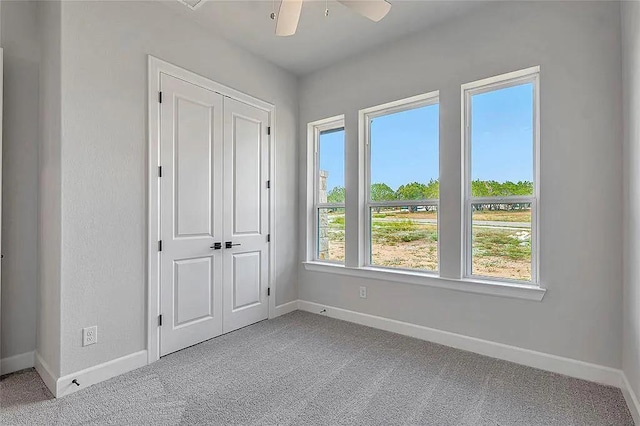 unfurnished bedroom featuring ceiling fan, light carpet, and a closet