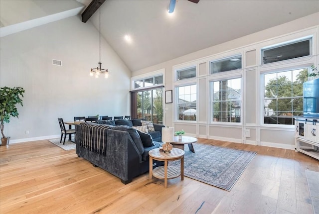 living room featuring high vaulted ceiling, visible vents, baseboards, light wood finished floors, and beamed ceiling