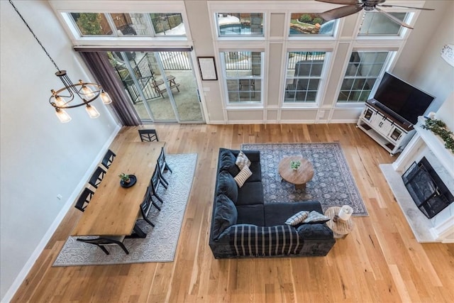 living room with a fireplace with flush hearth, a ceiling fan, baseboards, and wood finished floors