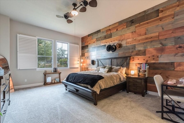 bedroom featuring carpet floors, ceiling fan, wooden walls, and baseboards