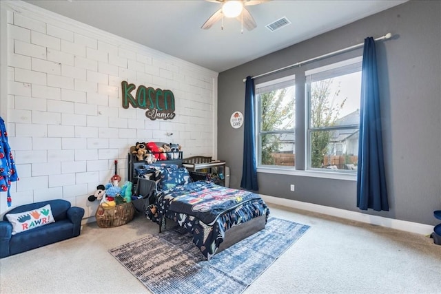 carpeted bedroom with an accent wall, visible vents, ceiling fan, and baseboards