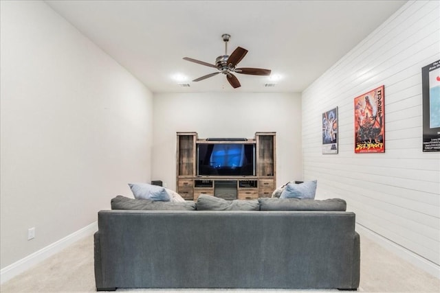 living area with light colored carpet, ceiling fan, and baseboards