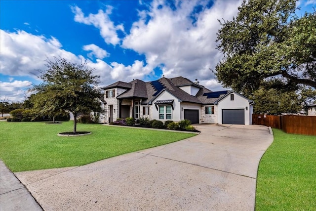 view of front of house with an attached garage, solar panels, fence, concrete driveway, and a front lawn