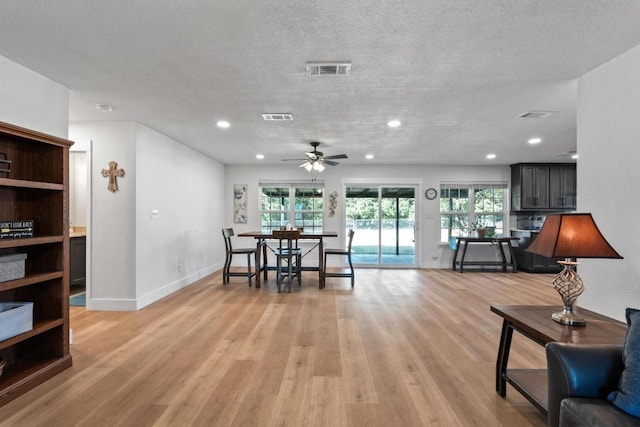 living room featuring a textured ceiling, light hardwood / wood-style flooring, and ceiling fan