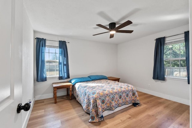 bedroom with ceiling fan, light wood-type flooring, and multiple windows